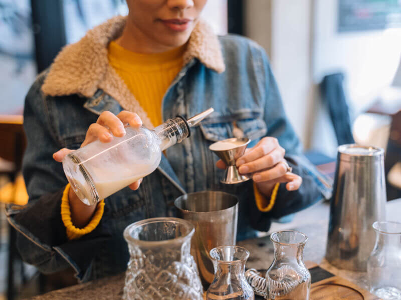 A woman pouring alcohol into a shot glass at a cocktail class.